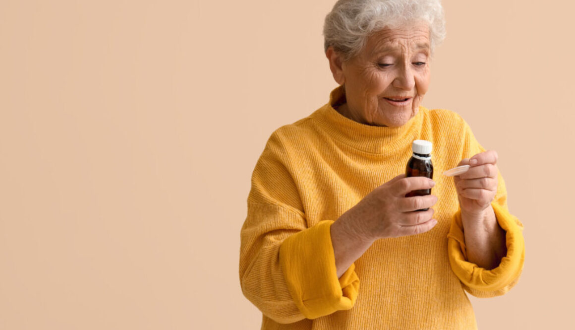 Ill senior woman taking cough syrup on beige background
