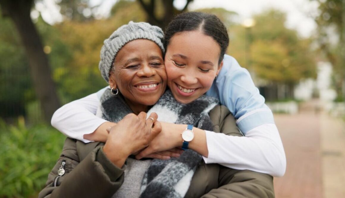 Caregiver, hug and park with old woman in a wheelchair for retirement, elderly care and physical therapy. Trust, medical and healthcare with portrait of patient and nurse in nature for rehabilitation