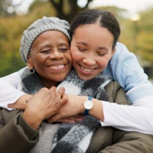 Caregiver, hug and park with old woman in a wheelchair for retirement, elderly care and physical therapy. Trust, medical and healthcare with portrait of patient and nurse in nature for rehabilitation