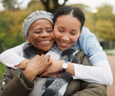 Caregiver, hug and park with old woman in a wheelchair for retirement, elderly care and physical therapy. Trust, medical and healthcare with portrait of patient and nurse in nature for rehabilitation